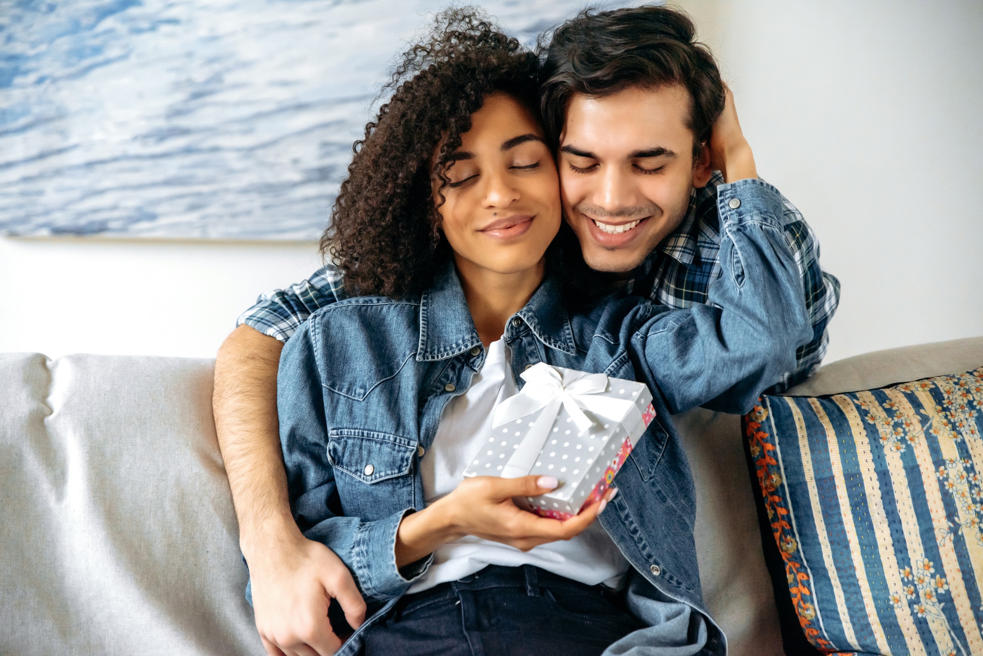 Birthday or anniversary gift. Mixed race guy gives a box with a gift to his beloved girlfriend